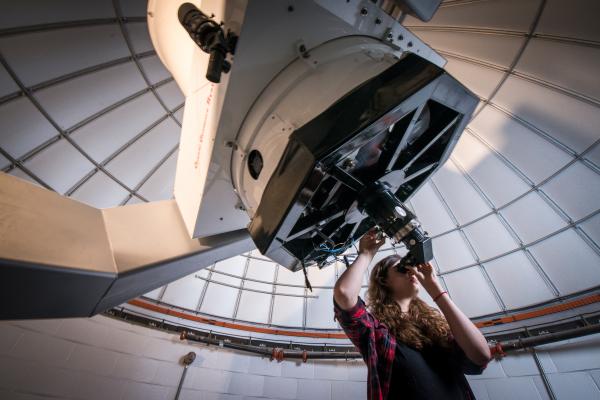Astronomy student looks through telescope in the observatory.